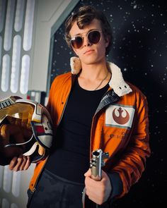 a young man wearing sunglasses and holding a star wars helmet