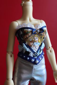 a doll is dressed in silver pants and a top