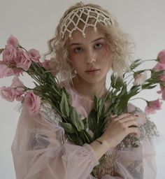 a woman wearing a tiara holding flowers in front of her face