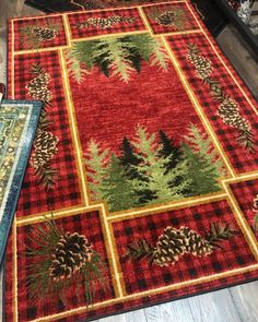 a red and green rug with pine trees on it, next to a blue area rug