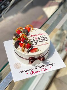 a birthday cake with strawberries and chocolates on top sitting on a glass table