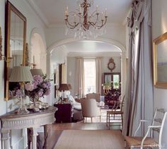 a living room filled with furniture and a chandelier hanging from the ceiling over a doorway