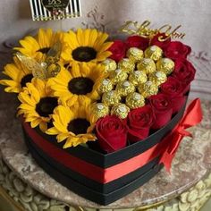 a heart shaped box filled with chocolates and sunflowers