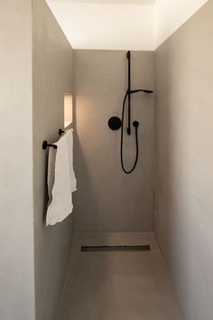 a bathroom with a shower head and towel hanging from it's side, next to a wall light