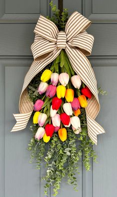 a wreath with tulips and other flowers hanging on a door