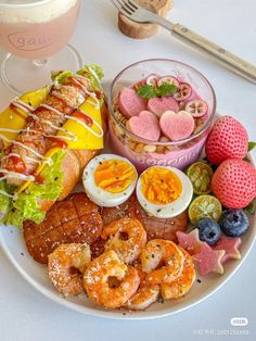 a white plate topped with lots of food and desserts next to a cup of coffee