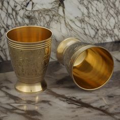 two gold cups sitting on top of a marble counter