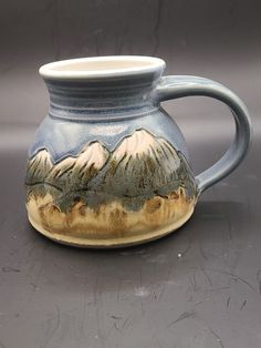 a ceramic mug with mountains painted on it