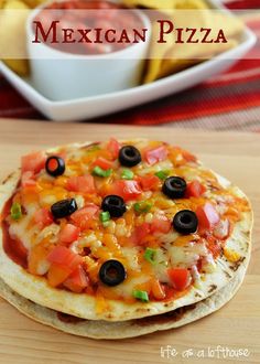 a tortilla with black olives, tomatoes and other toppings on it