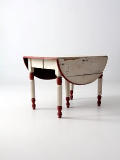 an old wooden desk with red trim on the top and bottom legs, sitting against a white wall