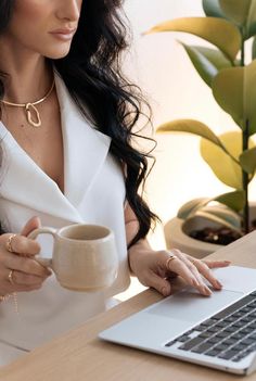 a woman sitting at a desk with a laptop and coffee cup