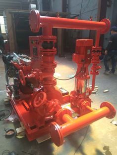 an orange pipe sitting on top of a floor next to other pipes and equipment in a warehouse