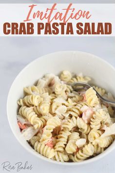 a white bowl filled with pasta and shrimp on top of a marble counter next to a spoon