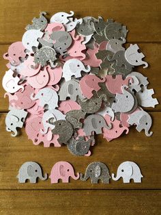 a pile of pink and silver elephant confetti on a wooden table next to some cut outs