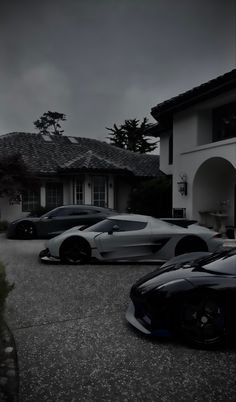 three sports cars parked in front of a house on a cloudy day with dark clouds