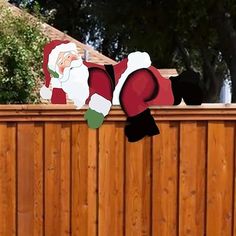 a santa clause standing on top of a wooden fence