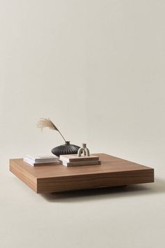 a wooden table topped with a book and vase