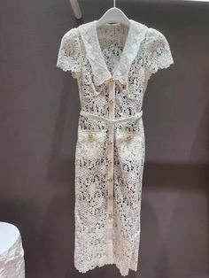 a white lace dress hanging on a hanger