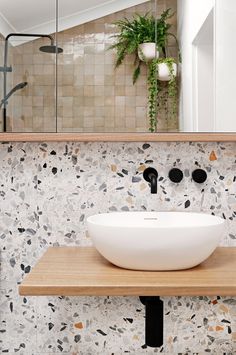 a white bowl sink sitting on top of a wooden counter next to a mirror above it