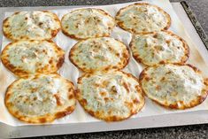 there are many small pizzas that are on the baking sheet, ready to be eaten