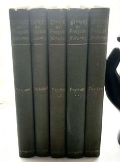 four black books sitting on top of each other in front of a figurine