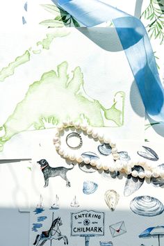 an image of a blue ribbon and bracelet on top of some papers with drawings in the background