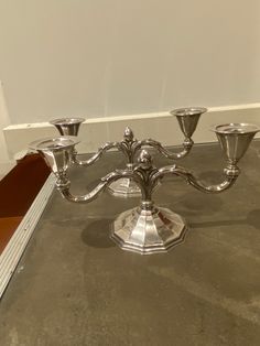 a silver candelabra sitting on top of a floor next to a wall