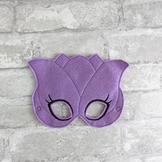 a purple cat mask with black eyes on a brick wall