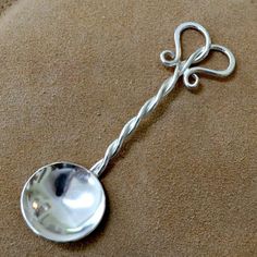 a metal spoon with a bow on it sitting on a brown surface next to a pillow