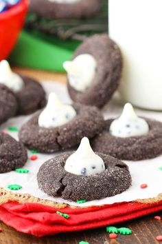 chocolate cookies with white frosting and ghost faces on them sitting on a red napkin