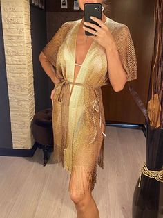 a woman is taking a selfie in a gold dress with fringes on it