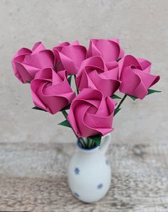 a white vase filled with pink paper flowers