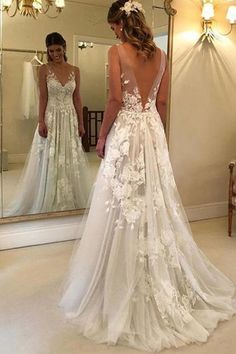 a woman standing in front of a mirror wearing a wedding dress with flowers on it