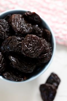 raisins in a blue bowl on a white tablecloth next to some dried raisins