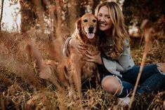 a woman sitting in the grass with her dog