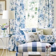 a living room with blue and white furniture in front of a window covered in curtains