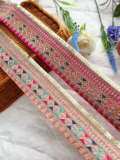 two different colored ribbons sitting next to each other on a white surface with flowers in the background