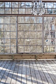 an empty room with wood flooring and large windows that have glass panes on them