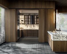 a large kitchen with marble counter tops and wooden cabinetry, along with two sinks