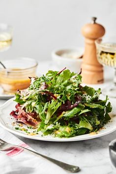 a white plate topped with salad next to wine glasses