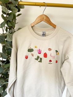 It's fall y'all! These sweatshirts are designed and machine embroidered in-house with cozy-little "cottage core" fall symbols for the autumn season. 🍂 If you would like a size not shown or different sweatshirt color, please message me with your request, I would be happy to make it happen! ☆ DESCRIPTION  Crew-neck "Pullover" Sweatshirt. 50% Cotton 50% Polyester  Color: Sand  Sizes: S, M, L, XL, 2XL  SHIPPING ☆ These sweatshirts are handmade and made to order, making each purchase individually stitched with care. Due to this, I do require a 3-5 day processing time per each order.   For high quantity orders of 4+ items, please allow a 7-10 day processing time. If you have a deadline, please message me upon order and I will make it my priority to expedite the production process!   RETURN POLI Cozy Fall Sweatshirt With Letter Embroidery, Cozy Sweatshirt With Letter Embroidery For Fall, Cozy Letter Embroidery Sweatshirt For Fall, Casual Embroidered Sweater For Fall, Cozy Long Sleeve Tops With Letter Embroidery, White Letter Embroidery Sweater For Fall, Embroidered Crew Neck Sweater For Fall, Embroidered Long Sleeve Sweatshirt For Fall, Embroidered Crew Neck Tops For Fall