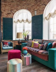 a living room filled with furniture and lots of window sill space next to a brick wall