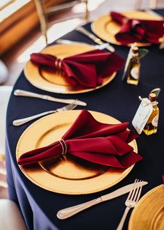 the table is set with red napkins and gold plates