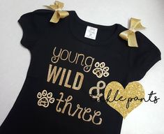 --♥♥-- The top of your birthday outfit will be full of glitter with the phrase 'Young WILD & Three'. Also included are cheetah/leopard paw prints. Each shoulder will feature a sewn gold bow. **This can be made in different colors** SIZING: Bodysuits are Carter's brand and smaller and are available in sizes 3m, 6m, 9m, 12m, 18m, 24m. Shirts are specific for embroidery and run true to size. Available sizes 2T, 3T, 4T, 5, 6 and 8. There is no size 7. CARE INSTRUCTIONS: Please handwash cold and Customizable Black Party Top, Customizable Black Party Tops, Customizable Black Top For Party, Gold Letter Print T-shirt For Party, Third Birthday Girl, Young Wild And Three, Birthday Girl Outfit, Tutu Outfits, Birthday Girl Shirt