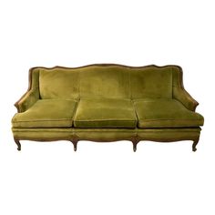 a green velvet couch with wooden legs and arm rests on an isolated white background for display