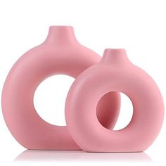 two pink vases sitting next to each other on a white surface, one is shaped like a circle