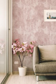 a living room with pink walls and flowers in a vase next to the couch on the floor