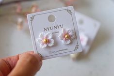 a pair of tiny crochet flower earrings in white and pink with gold centers