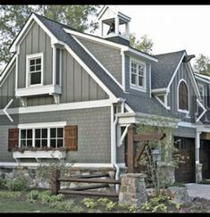 a gray house with brown shutters and white trim on the front door is shown