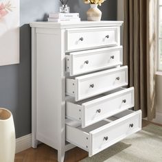 a white dresser with five drawers and a vase filled with flowers on top of it